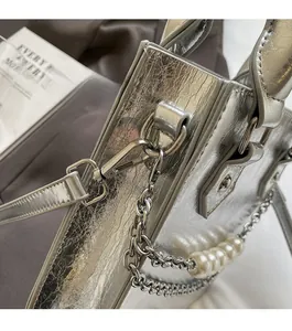 Détail du sac à main argenté métallisé avec texture plissée et chaîne en perles élégante