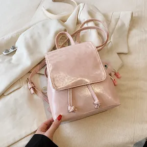 Detalle de la mochila de cuero PU rosa brillante con cierre de cordón y colgante de pompón