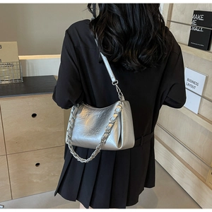 Détail du sac à bandoulière argenté plissé avec chaîne métallique porté par un modèle