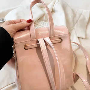 Detalle de una mochila de cuero sintético rosa mostrando el asa y el anillo de metal dorado