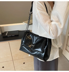 Detail of glossy oil wax leather tote with silver bow accent and chain shoulder strap