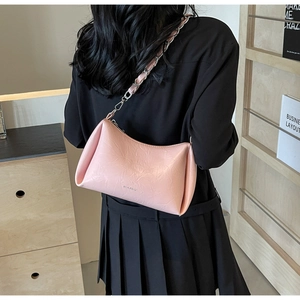 Sac sous le bras en cuir plissé rose avec chaîne dorée porté par une femme