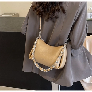 Détail du sac à bandoulière plissé beige avec chaîne argentée sur une veste grise