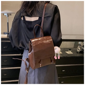 Deep brown glossy patent leather backpack with drawstring closure and pink plush charm