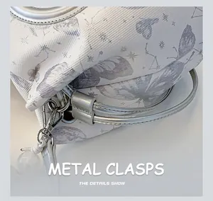 Close-up of silver metal hook and butterfly print on white canvas handbag detail