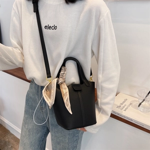 Fashionable black pebble leather bucket bag with decorative silk scarf and shoulder strap