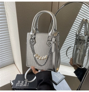 Détail du mini sac argenté avec chaîne de perles et poignées métalliques élégantes