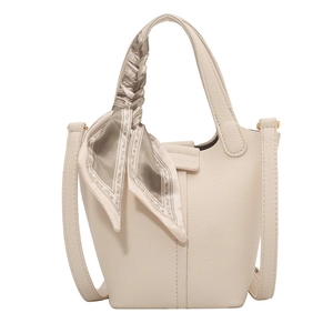 Minimalist beige bucket bag with lychee texture and decorative silk scarf on handle