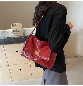 Detail of burgundy patent leather tote with silver bow and classic chain strap