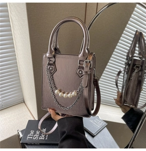 Détail d'un sac à main argenté métallisé avec texture cuir et chaîne de perles