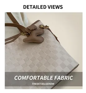 Gros plan sur le sac fourre-tout beige matelassé avec garniture en cuir brun et breloque ours