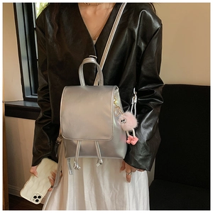 Detail of silver metallic backpack with drawstring closure and pink plush charm