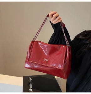 Detail of red oil wax leather tote with silver bow metal clasp and chain strap