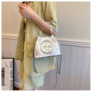 Detail of beaded pearl handle and butterfly pattern on a versatile crossbody bucket bag
