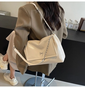 Detail of soft leather tote featuring a silver metal bow and chain shoulder strap