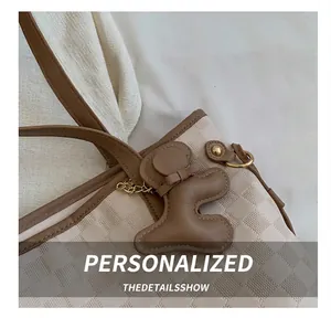 Détail du sac cabas à carreaux beige avec une jolie breloque ours en cuir marron