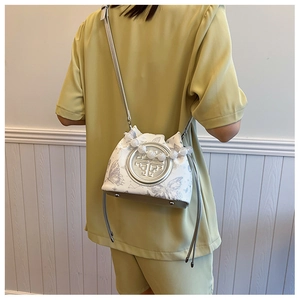 Detail of white butterfly bucket bag with beaded handle and silver logo on light green outfit