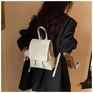 Close-up of cream PU leather backpack with drawstring closure and pink plush charm