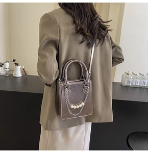 Détail du sac texturé métallique avec chaîne de perles élégante et poignée rigide
