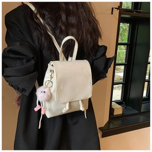 Close-up of beige PU leather mini backpack with drawstring closure and pink plush charm