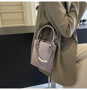 Détail du sac bandoulière rose métallique avec chaîne en perles et poignée chic