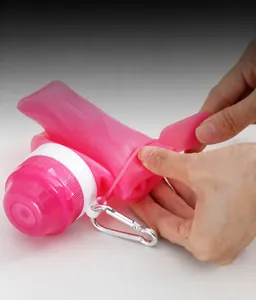 Close-up of pink collapsible silicone water bottle being folded with metal carabiner