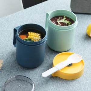 Close-up of portable soup cups with leak-proof lids and folding spoons on a gray tablecloth