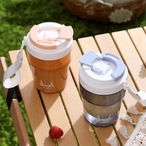 Collapsible silicone sports bottles in orange and grey on a wooden outdoor picnic table