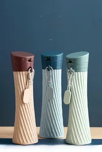 Three silicone portable water bottles in apricot, blue, and green on a wooden surface