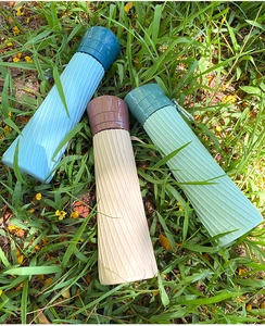 Outdoor view of collapsible silicone water bottles in blue, beige, and green on green grass