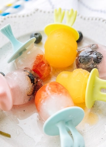 Détail de moules à glace colorés avec poignées oreilles de lapin et bâtons de fruits