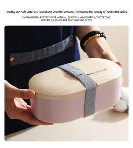 Detail view of pink oval lunch box with wood-textured lid and grey elastic strap