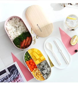Detail view of double-layer bento box with wood-style lid and compartments for food