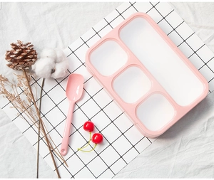 Close-up of pink compartmentalized lunch box with transparent lid and pink spoon