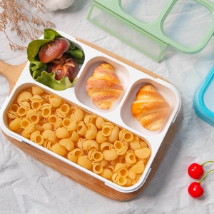 Three-compartment plastic bento box on a wooden tray for healthy meal prep and portion control