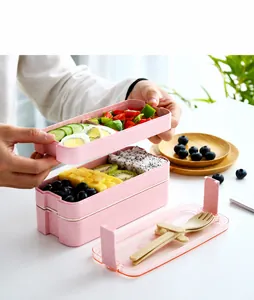 Detailed view of a pink double-layer lunch box with built-in cutlery storage and utensils