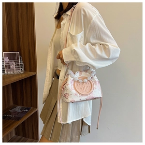 Detailed view of white bucket bag with pink butterfly prints and beaded handle on model
