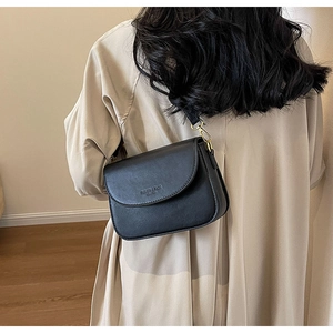 Borsa a tracolla classica in pelle nera con dettagli dorati indossata da una modella
