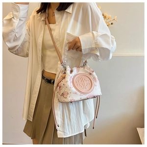 Detail of white bucket bag with pink butterfly print and beaded top handle strap