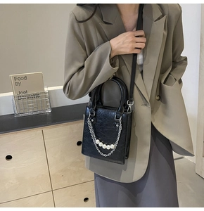Détail du sac à main noir en cuir ciré avec des perles et une chaîne argentée chic