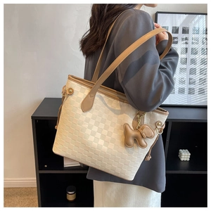Détail du sac cabas à damier blanc cassé avec anses en cuir marron et breloque chiot