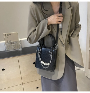 Détail du sac à main noir en cuir PU avec chaîne argentée et cinq perles élégantes