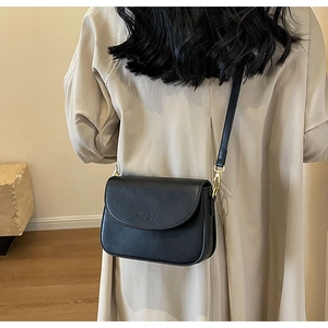 Vista posteriore di una modella con borsa a tracolla in pelle nera opaca e oro
