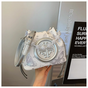 Detailed macro of a white butterfly print bucket bag with elegant pearl beaded handle