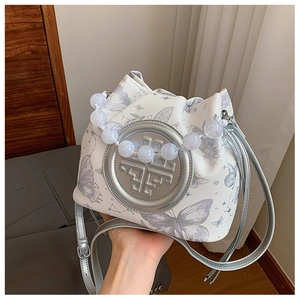 Detail of white canvas bucket bag with butterfly prints and elegant beaded handle