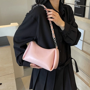 Sac bandoulière rose en similicuir avec chaîne argentée dans un décor d'intérieur chic