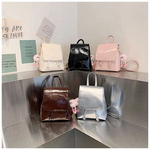 Detailed display of mini crossbody backpacks in five glossy colors with plush ball charms