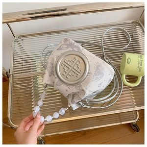Detail of white canvas bucket bag with butterfly print and marble beaded handle