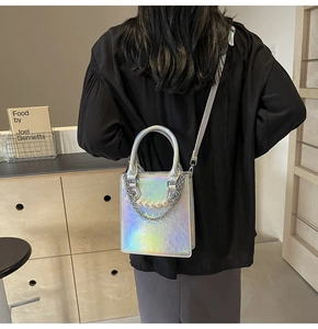 Détail du sac à main holographique argenté avec chaîne de perles porté par un modèle