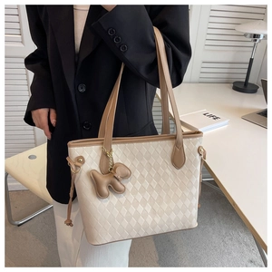 Vue détaillée du sac cabas matelassé beige avec anses brunes et breloque chien